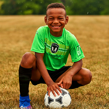 male soccer player kneeling with ball